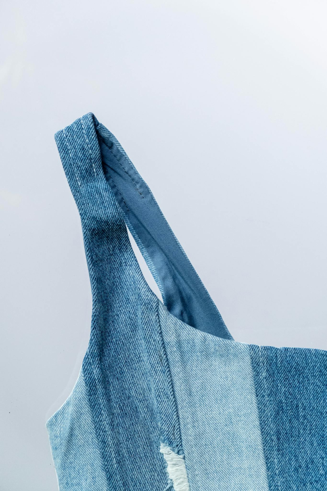 Close-up of a stylish denim dress strap, showcasing texture and fashion elements.